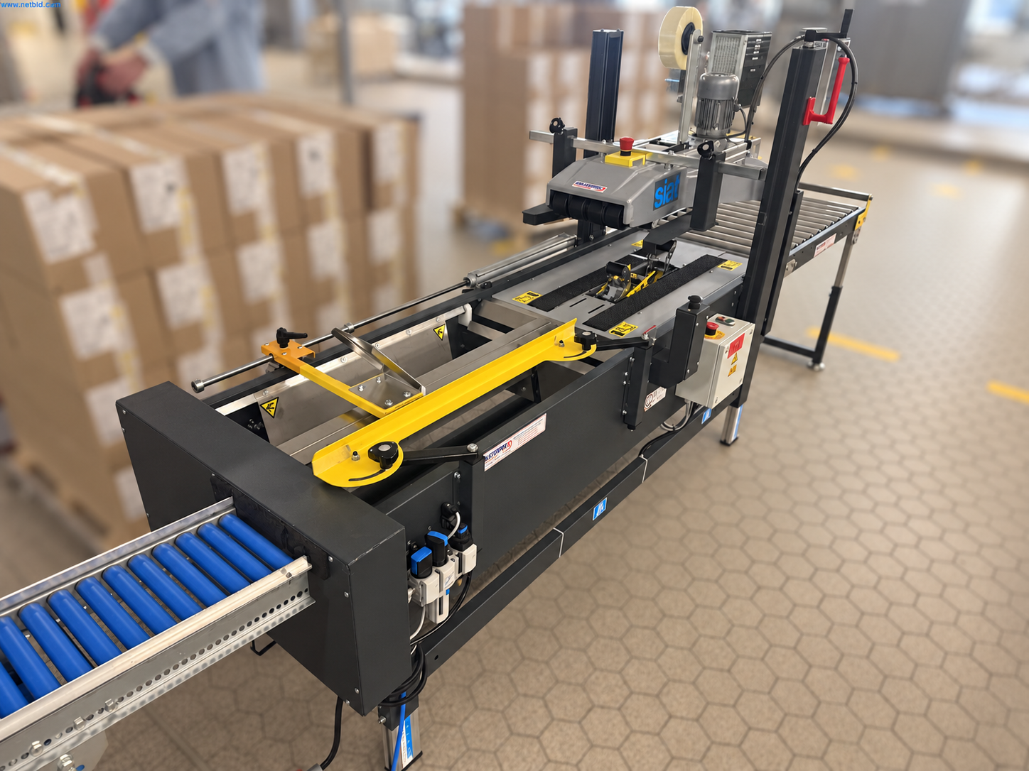 SIAT PS50 T/B Kartonverschließmaschine mit verstellbaren Kartonführungen und Rollenbahnen in der Gesamtansicht.