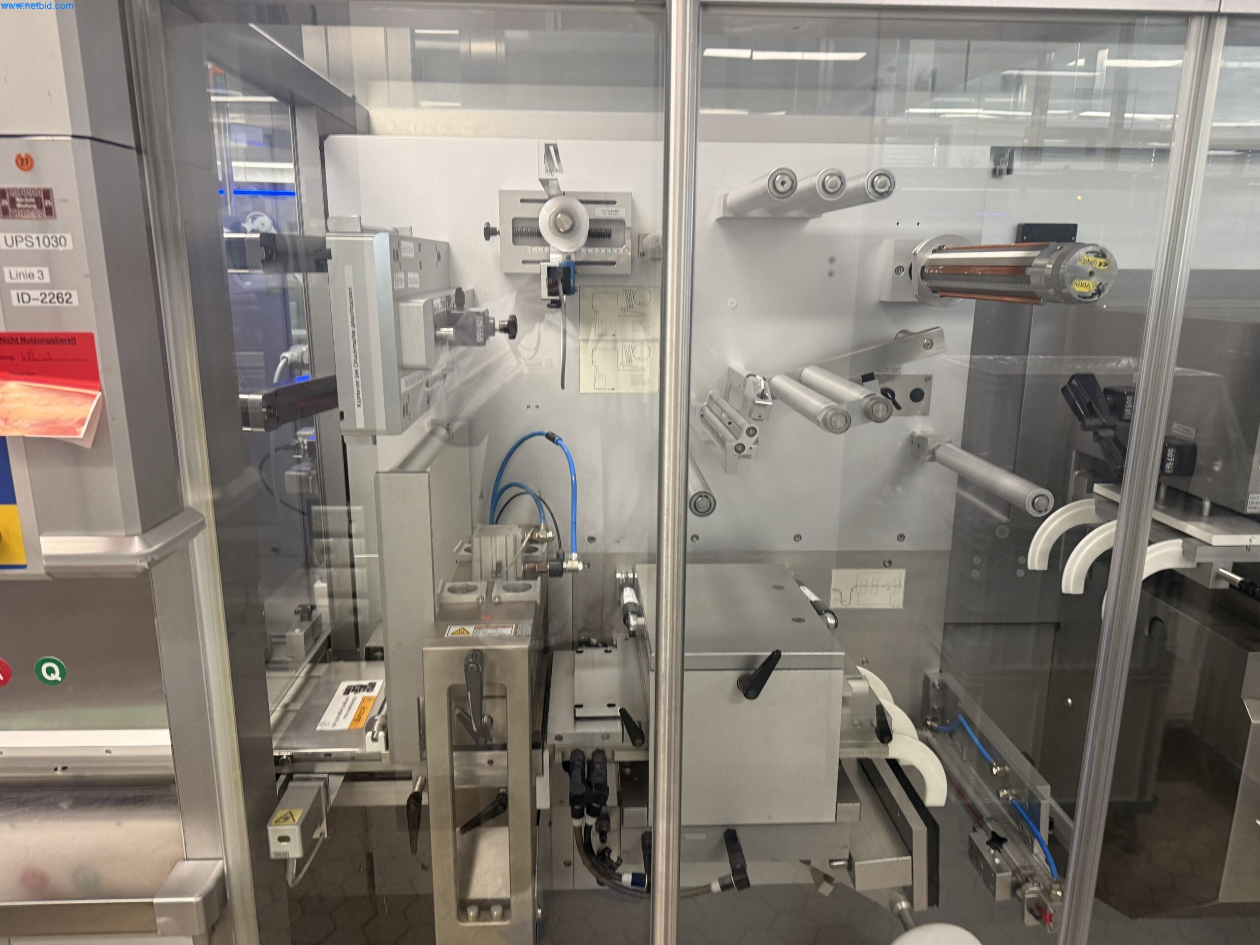 Siegelstation der Uhlmann UPS1030 Blistermaschine mit Folienführung hinter transparenten Schutztüren.